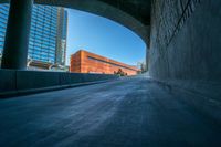 an empty walkway leads out to a building in the distance with other buildings and tall towers in the background