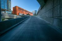 an empty walkway leads out to a building in the distance with other buildings and tall towers in the background