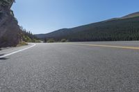 two yellow lines on road beside mountain and lake as seen from vehicle point of view