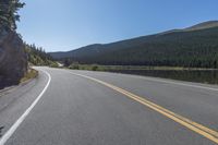 two yellow lines on road beside mountain and lake as seen from vehicle point of view