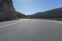 two yellow lines on road beside mountain and lake as seen from vehicle point of view