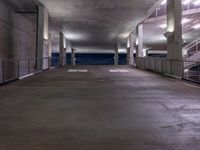 an empty parking garage has a ramp on one side and stairs and railings to the left