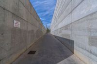 the empty parking lot in front of a wall with apartment buildings on it and a skateboarder on a ramp