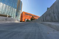 an empty road and a wall with several buildings in the background behind it are blue skies