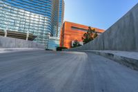 an empty road and a wall with several buildings in the background behind it are blue skies