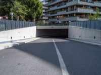 a large concrete tunnel in the middle of an empty street between two buildings with windows