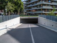 a large concrete tunnel in the middle of an empty street between two buildings with windows