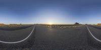 a wide road that runs through a desert landscape at sunset with bright sun flares