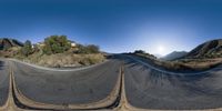 the 360 - angle view shows a straight road in front of a building and mountains