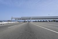 a highway with a truck passing underneath the overpass and a bridge crossing it and buildings on the side