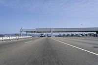 a highway with a truck passing underneath the overpass and a bridge crossing it and buildings on the side