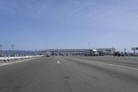 a highway with a truck passing underneath the overpass and a bridge crossing it and buildings on the side