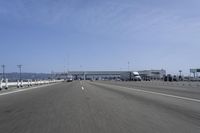 a highway with a truck passing underneath the overpass and a bridge crossing it and buildings on the side