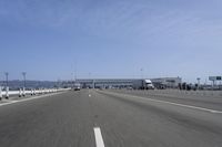 a highway with a truck passing underneath the overpass and a bridge crossing it and buildings on the side
