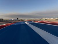 a racing track with red, white and blue stripes and a passenger plane in the background