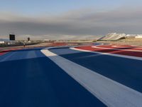 a racing track with red, white and blue stripes and a passenger plane in the background