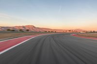 a photo of a dirt race track with sun setting in the distance of the track