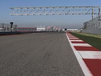 red and white track lines next to silver metal poles with green grass in front of blue sky