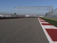 red and white track lines next to silver metal poles with green grass in front of blue sky