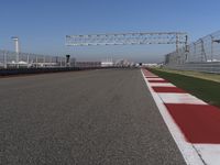 red and white track lines next to silver metal poles with green grass in front of blue sky