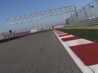 red and white track lines next to silver metal poles with green grass in front of blue sky