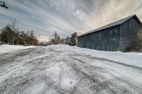 a building sitting across from snow covered street next to a wooden shed sitting in the snow