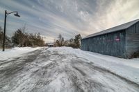 a building sitting across from snow covered street next to a wooden shed sitting in the snow