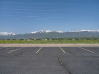 an empty parking lot with the mountains in the background and snow capped mountains in the distance