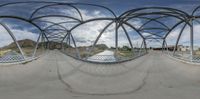 a 360 - angle photo of a street with metal structures and cloudy blue sky above