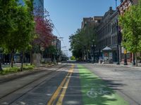 the green paint is painted on a bike path in front of an office building and large, trees