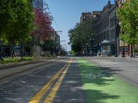 the green paint is painted on a bike path in front of an office building and large, trees