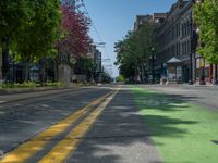 the green paint is painted on a bike path in front of an office building and large, trees