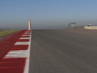 an empty track at a motorsports club with some red and white stripeing on it