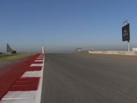 an empty track at a motorsports club with some red and white stripeing on it