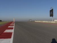 an empty track at a motorsports club with some red and white stripeing on it