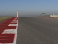 an empty track at a motorsports club with some red and white stripeing on it