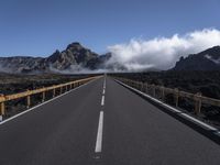 a highway in front of a mountain with clouds in the sky and fog in the distance