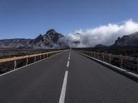 a highway in front of a mountain with clouds in the sky and fog in the distance