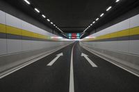 the empty road is in the middle of a tunnel with lights on either side of it