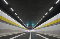 the empty road is in the middle of a tunnel with lights on either side of it