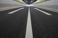 the empty road is in the middle of a tunnel with lights on either side of it