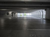 an empty parking garage with a few doors open in a big building on a sunny day