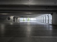 an empty parking garage with a few doors open in a big building on a sunny day