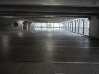 an empty parking garage with a few doors open in a big building on a sunny day