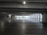 an empty parking garage with a few doors open in a big building on a sunny day