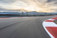 a photo of a dirt race track with sun setting in the distance of the track