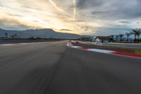 a photo of a dirt race track with sun setting in the distance of the track