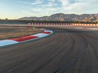 a photo of a dirt race track with sun setting in the distance of the track