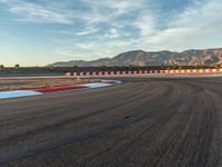 a photo of a dirt race track with sun setting in the distance of the track