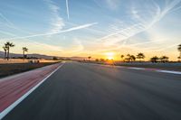 a photo of a dirt race track with sun setting in the distance of the track